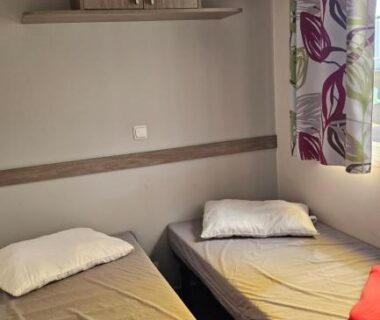 Chambre avec deux lits simples et rangement dans le mobile-home les pieds dans l'eau