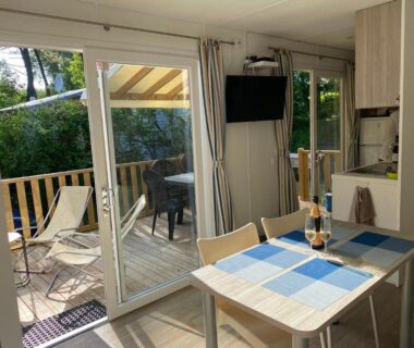 Intérieur ouvert sur terrasse avec table et chaises dans le Mobile home luxe au calme