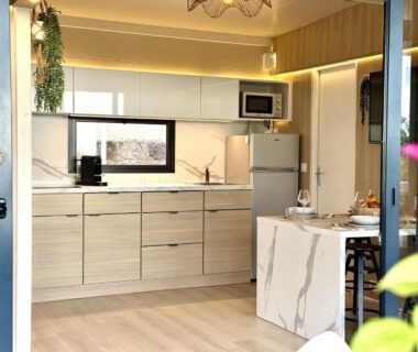 Intérieur cuisine équipée avec baie vitrée vers terrasse du mobile-home magnifique vue mer camping 4 étoiles