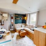 Séjour lumineux avec canapé et kitchenette dans le Mobile home neuf climatisé 3 chambres sur le Bassin d'Arcachon