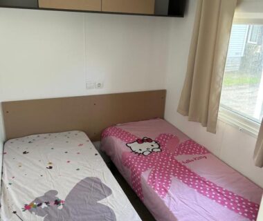 Chambre avec deux lits simples et fenêtre dans le mobile home sirène luxe Camping le Bosc
