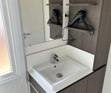 Salle de bain avec lavabo miroir et sèche-cheveux du mobile home sirène luxe au Camping le Bosc
