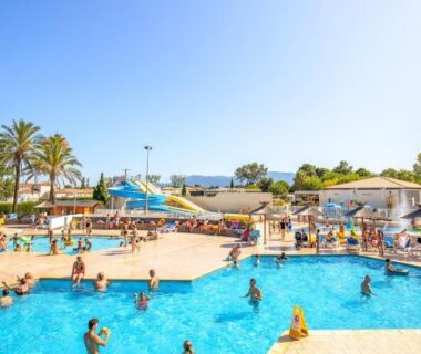Piscine avec toboggans et palmiers au Mobile home sirène luxe du Camping le Bosc