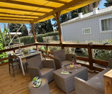 Terrasse couverte avec salon extérieur et table du Mobile home sirène luxe Camping le Bosc 4 étoiles 3 chambres