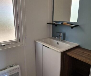 Salle de bains avec lavabo miroir et étagère dans le Mobilehome familial