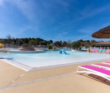 Piscine avec toboggan et transats roses au camping près du Mobilehome familial