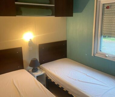 Chambre avec deux lits simples et lampe dans le Mobilhome