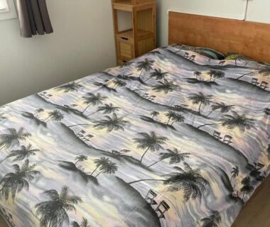 Dans la chambre lit avec couette motifs palmiers dans le Mobilhome