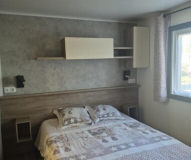 Intérieur chambre avec lit double et rangements dans le Mobilhome