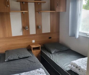 Chambre intérieure avec deux lits simples et étagères du mobilhome
