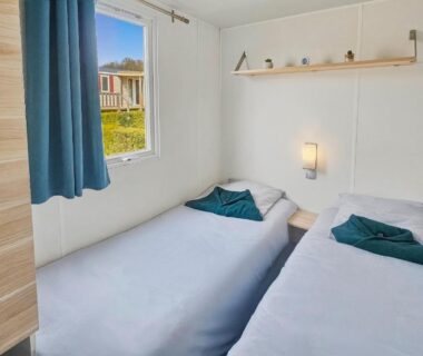 Chambre avec deux lits simples et fenêtre dans le Mobilhome