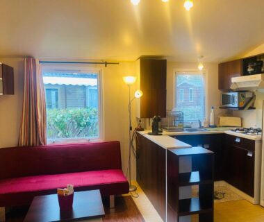 Séjour avec canapé rouge et kitchenette du Mobilhome