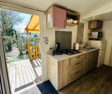 Entrée et kitchenette ouvrant sur terrasse en bois du Mobilhome 228 proche du Lac