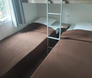 Chambre intérieure avec deux lits simples et échelle vers mezzanine dans le Mobilhome 228 proche du Lac