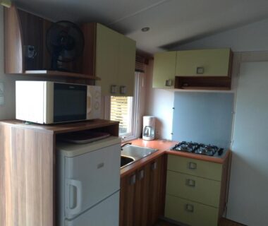 Cuisine compacte avec réfrigérateur micro-ondes évier et plaque de cuisson dans le Mobilhome 3 chambres Clim 6 Personnes