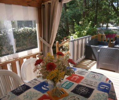 Terrasse avec table fleurie et salon extérieur du Mobilhome 3 chambres tout confort proche de la plage