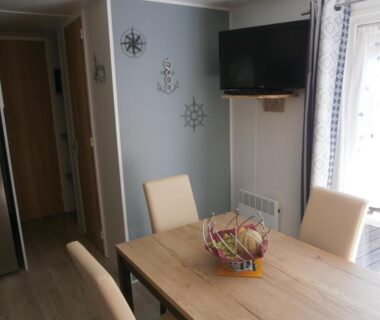 Intérieur avec table à manger télévision et décor marin dans le Mobilhome 3 chambres tout confort proche de la plage