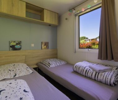 Intérieur chambre avec lits simples et fenêtre donnant sur jardin dans le Mobilhome 373