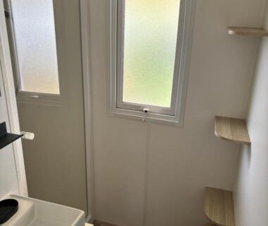 Salle de bain avec lavabo fenêtre et étagères dans le Mobilhome 379 camping 4 étoiles Siblu Lattes