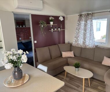 Salon avec canapé d'angle et table basse dans le mobilhome 379 du camping 4 étoiles Siblu Lattes