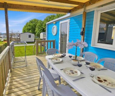 Terrasse en bois avec table dressée et chaises sur la parcelle du Mobilhome