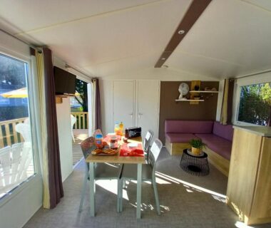 Intérieur avec coin repas et banquette dans le Mobilhome 4 pers 2 ch Centre Aquatique