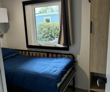 Intérieur chambre avec lit double et fenêtre au Mobilhome 400m de la plage