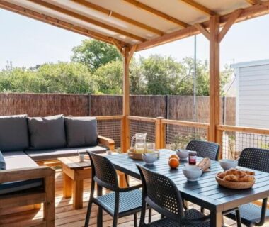 Terrasse couverte avec table à manger et canapé du Mobilhome 400m de la plage Camping 5 étoiles