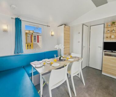 Coin repas intérieur avec banquette bleue et table dressée dans le Mobilhome