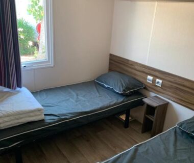 Chambre avec deux lits simples et fenêtre dans le Mobilhome 5 VO32