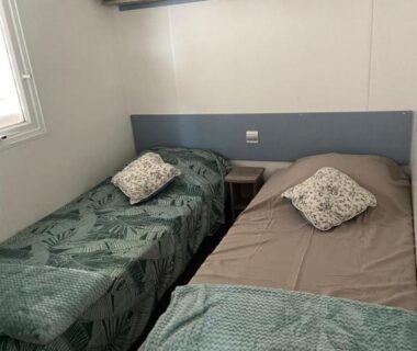 Chambre avec deux lits simples et étagère de rangement dans le Mobilhome 516