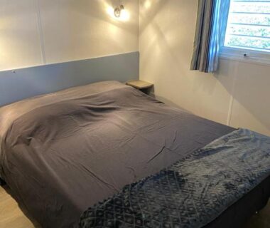 Chambre avec lit double et lampe près de la fenêtre dans le Mobilhome 516
