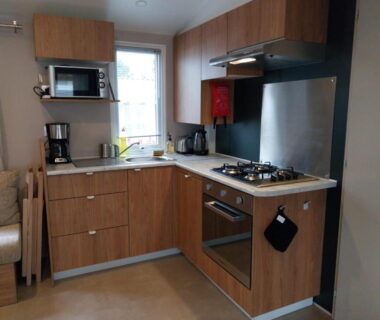 Coin cuisine avec four gaz micro-ondes cafetière et évier dans le Mobilhome 6-8 personnes Clim