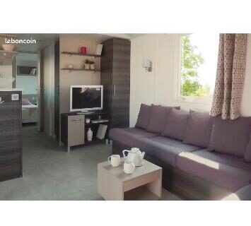 Salon avec canapé, table basse et télévision dans le mobilhome 6 et 4 places terrasses couvertes Les Dunes de Contis