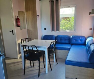 Séjour avec banquette bleue table et chaises dans le mobilhome 6 personnes du camping la falaise