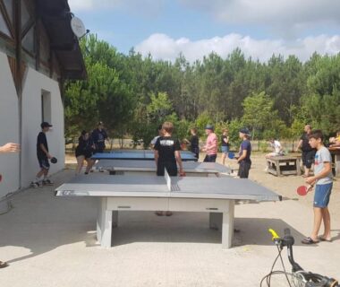 Espace extérieur avec tables de ping-pong et joueurs au camping Les Vignes