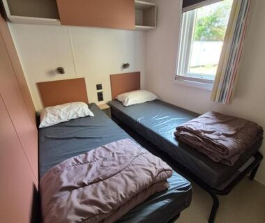 Chambre avec deux lits simples et fenêtre dans le mobilhome 6 personnes domaine de la yole