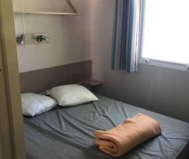 Chambre avec lit coussins et fenêtre dans le Mobilhome 6 place aureilhan