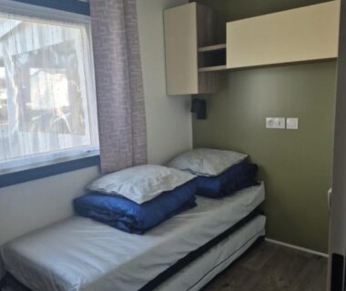 Chambre avec lits gigognes et rangement mural dans le mobilhome