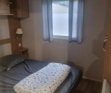 Chambre intérieure avec lit double rideaux et lampe du mobilhome