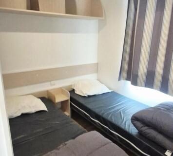 Chambre avec deux lits simples et rangements dans le Mobilhome