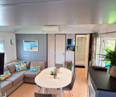 Salon avec canapé d'angle et table à manger dans le Mobilhome Argèles Plage à 500m Camping DEL MAR