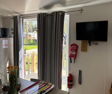 Intérieur mobilhome avec table rideaux et télévision dans le Mobilhome Avengers Camping du Ried