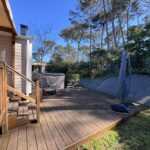 Terrasse en bois avec mobilier extérieur et parasol du Mobilhome Calina au camping Les Viviers Cap-Ferret