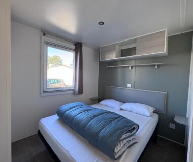 Chambre double avec lit et fenêtre dans le mobilhome Calina au camping Les Viviers Cap-Ferret