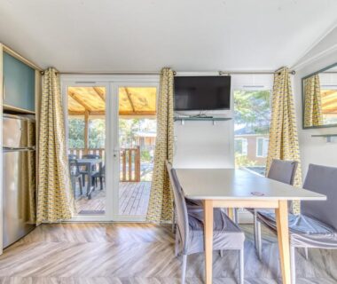 Séjour avec baie vitrée et terrasse équipée du Mobilhome Camping Siblu les Viviers