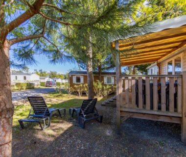 Terrasse en bois avec transats sous les pins du Mobilhome Camping Siblu les Viviers