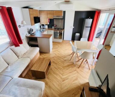 Salon ouvert avec canapé table et cuisine équipée du mobil-home Canet en Roussillon