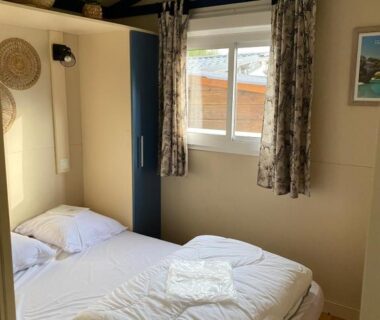 Chambre avec lit double et serviettes dans le Mobilhome Chalet à Ruoms