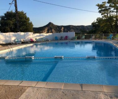 Piscine extérieure et terrasse avec montagnes en arrière-plan au Mobilhome Chalet